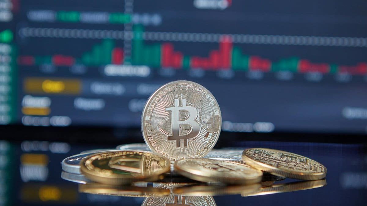 Bitcoin cryptocurrency coins in focus with a blurred stock market chart in the background, representing investment and finance.