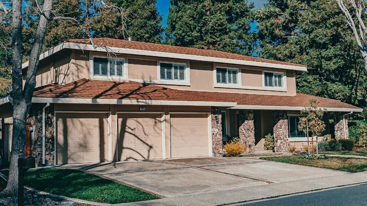 Spacious two-story house with a manicured front lawn and driveway on a sunny day.