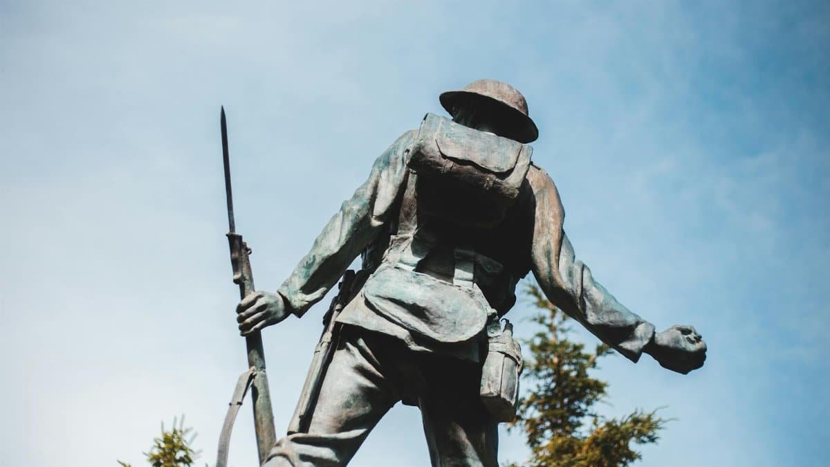 Bronze sculpture of World War I soldier holding a rifle, with blue sky backdrop.