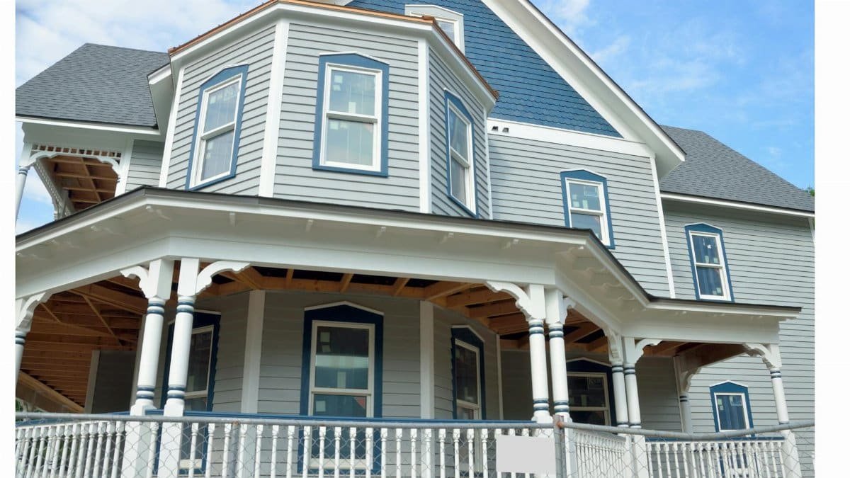 Charming Victorian-style home with gray wood siding and blue accents seen from the street.