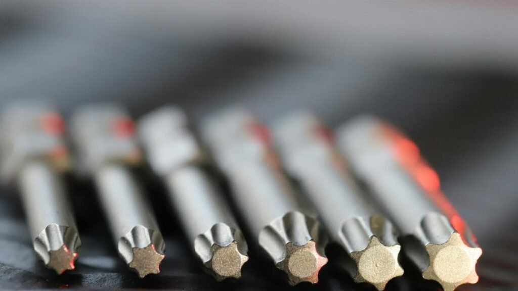 Macro shot of metal precision drill bits with star-shaped tips in a row, emphasizing detail and craftsmanship.