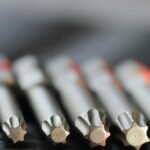 Macro shot of metal precision drill bits with star-shaped tips in a row, emphasizing detail and craftsmanship.