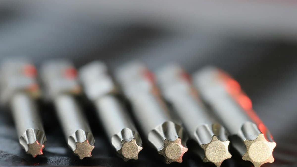 Macro shot of metal precision drill bits with star-shaped tips in a row, emphasizing detail and craftsmanship.