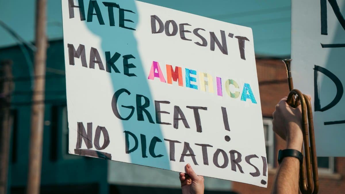 A protest sign with the message 'Hate Doesn't Make America Great!' during a daytime demonstration.