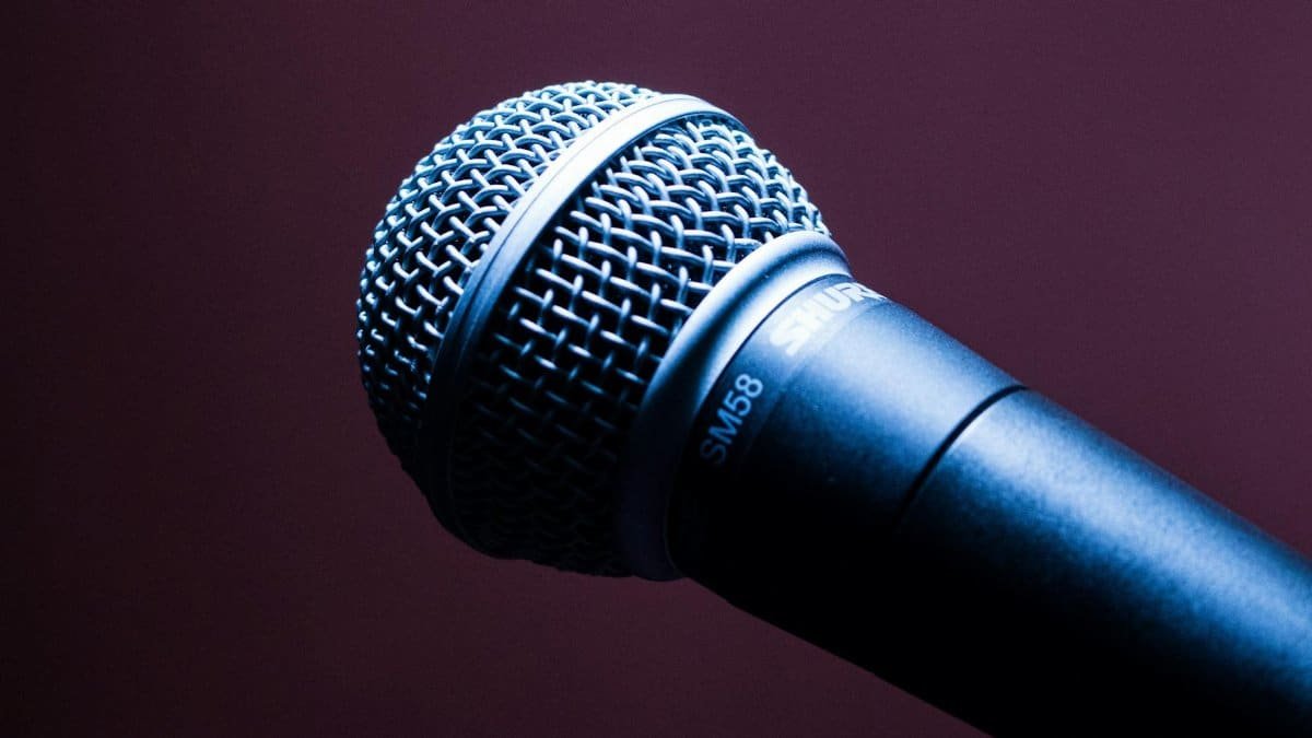 A detailed close-up of a Shure SM58 microphone with an artistic blue lighting effect.