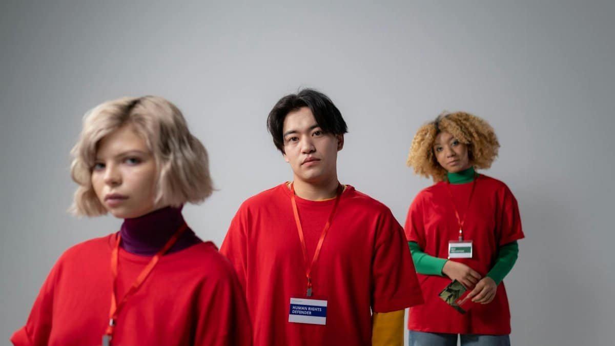 Three volunteers in red shirts engaged in service work, showcasing diversity and teamwork.