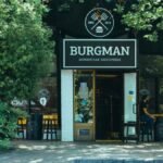 Exterior view of Burgman restaurant with outdoor seating area in a leafy urban setting.