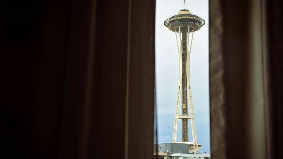 View of Seattle's Space Needle framed by curtains, showcasing iconic architecture.