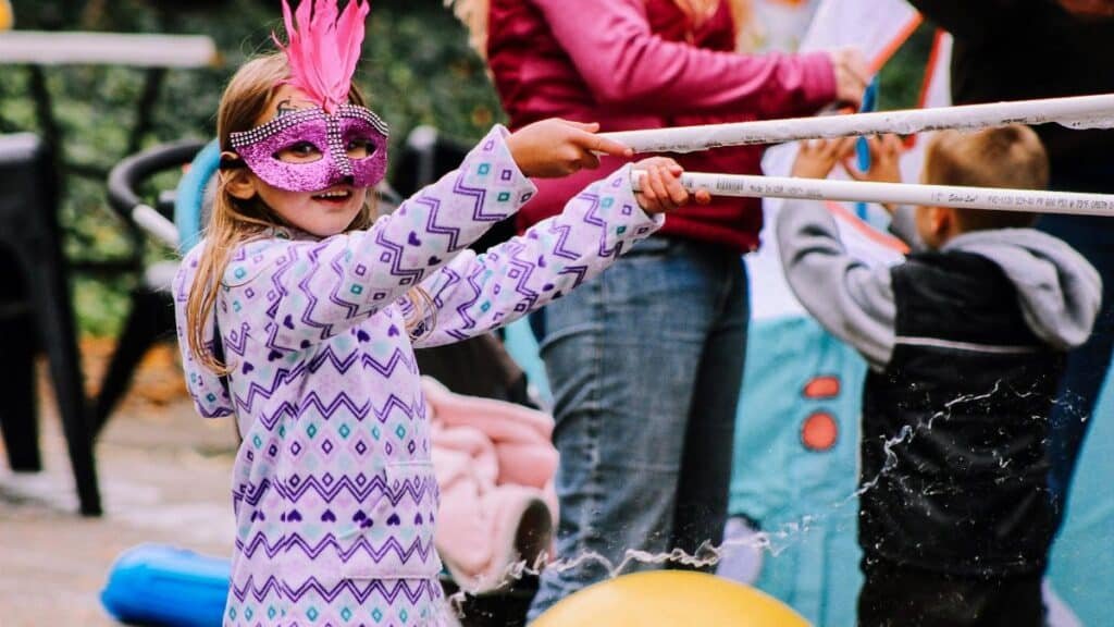 Young girl enjoying a playful water activity at an outdoor festival in Wheeling, WV.
