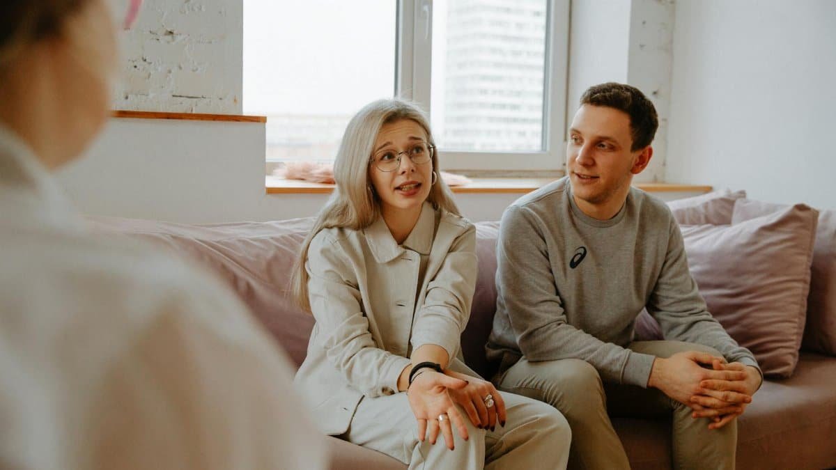 A couple and therapist engaged in a discussion during a therapy session indoors.