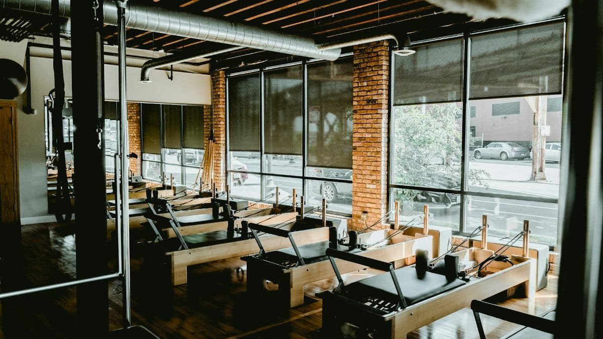 Bright pilates studio with reformer machines and natural light ambiance.