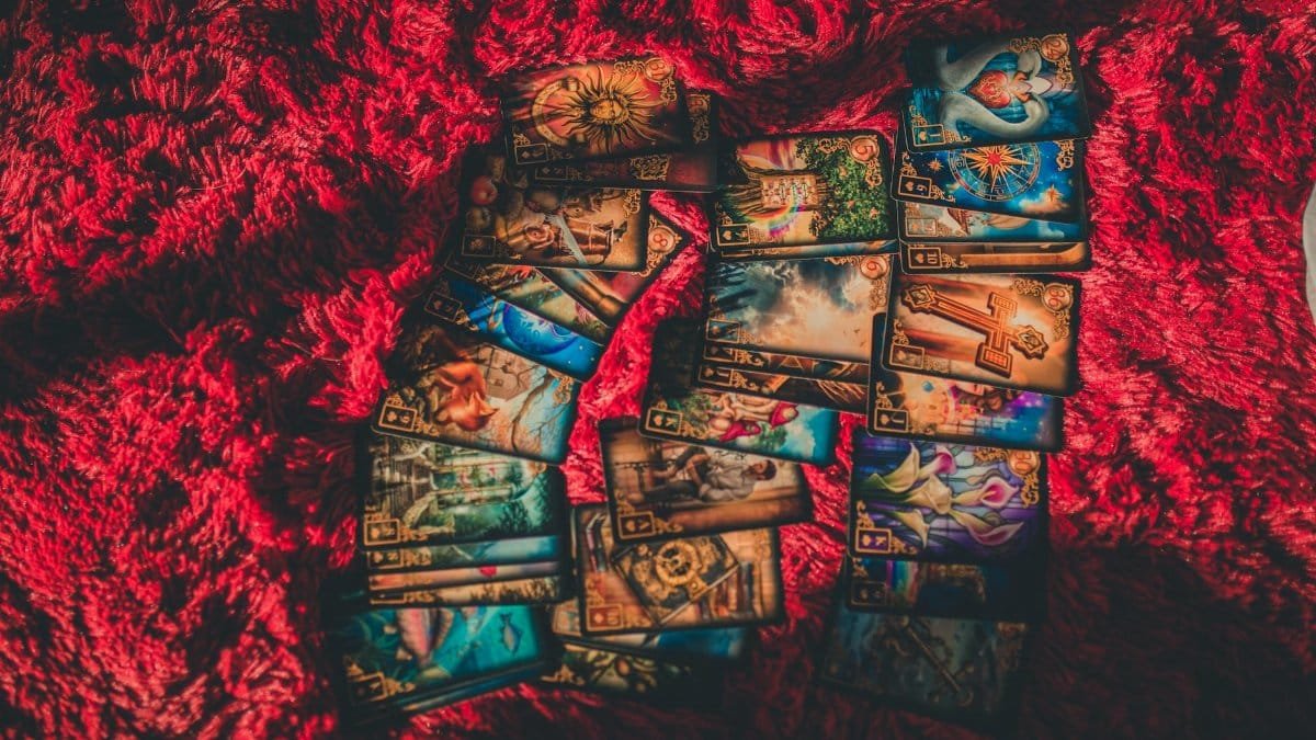 A collection of tarot cards laid out on a textured red fabric, evoking mystical and fortune-telling themes.