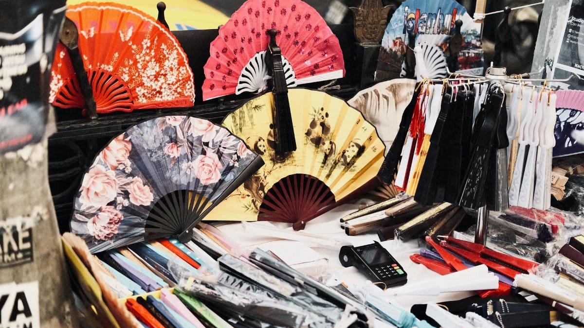 Vivid display of traditional hand fans at an outdoor market stall, showcasing diverse designs and colors.