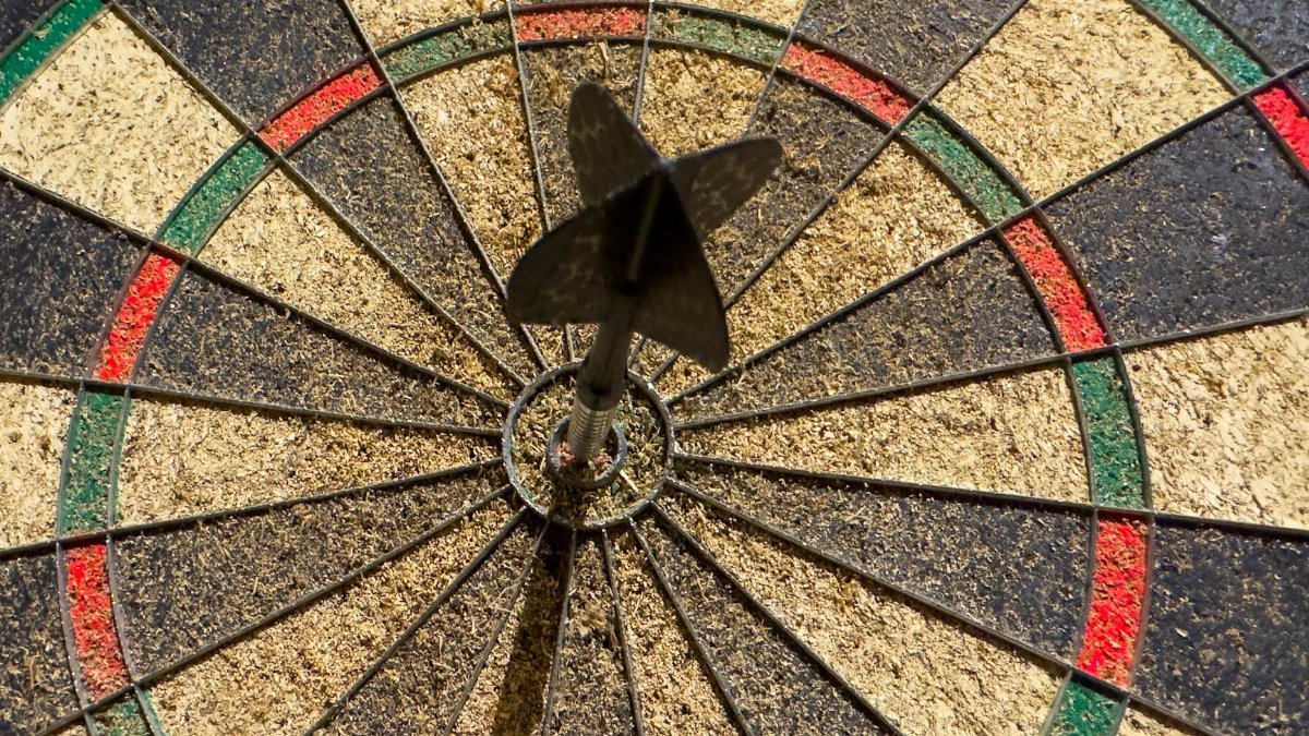 Dart perfectly hitting the bullseye on a dartboard, showcasing precision and success.