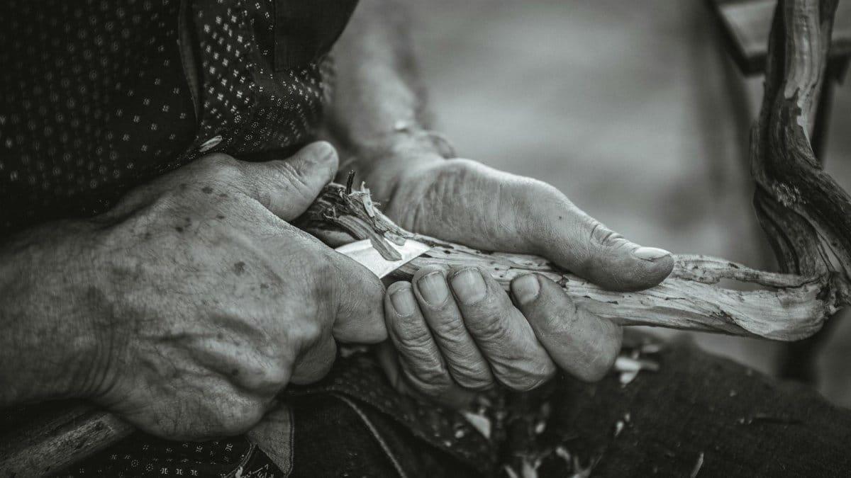 Close-up of hands skillfully carving wood, showcasing craftsmanship.