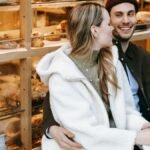 Happy couple enjoying a cozy coffee date outside a bakery with warm drinks.