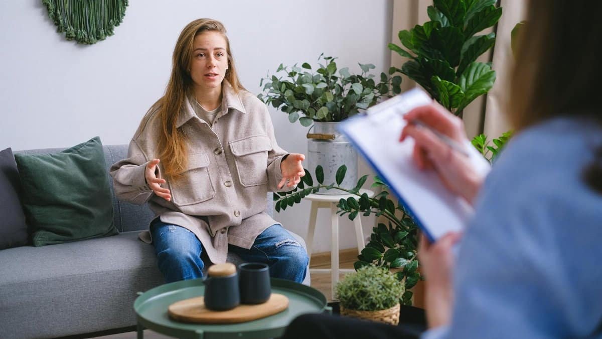 A woman engages in a therapy session, discussing issues with a counselor inside a modern office.