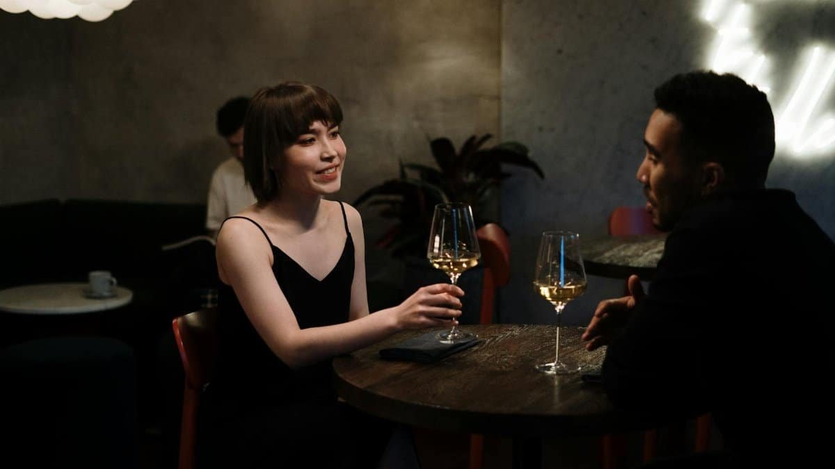 Couple enjoying a date night with white wine in a modern restaurant.