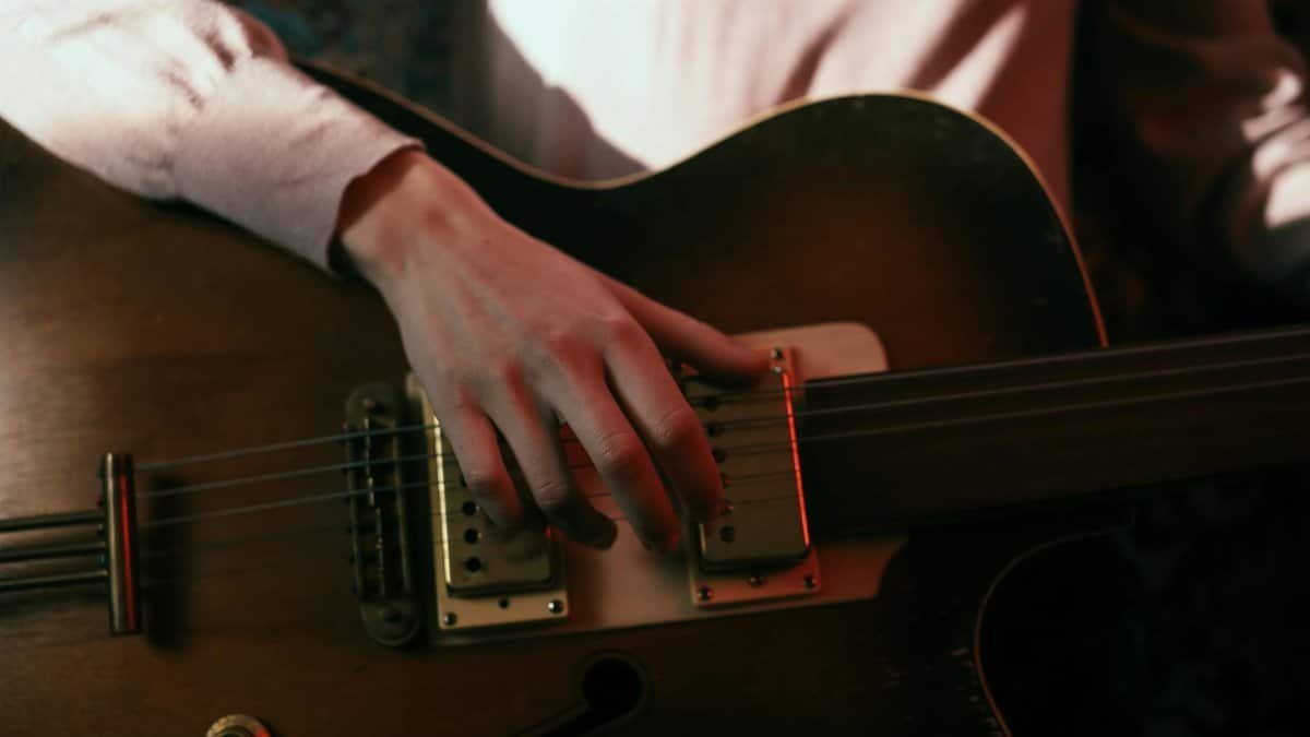 A close-up view of a person strumming an acoustic guitar, focusing on hand and strings.