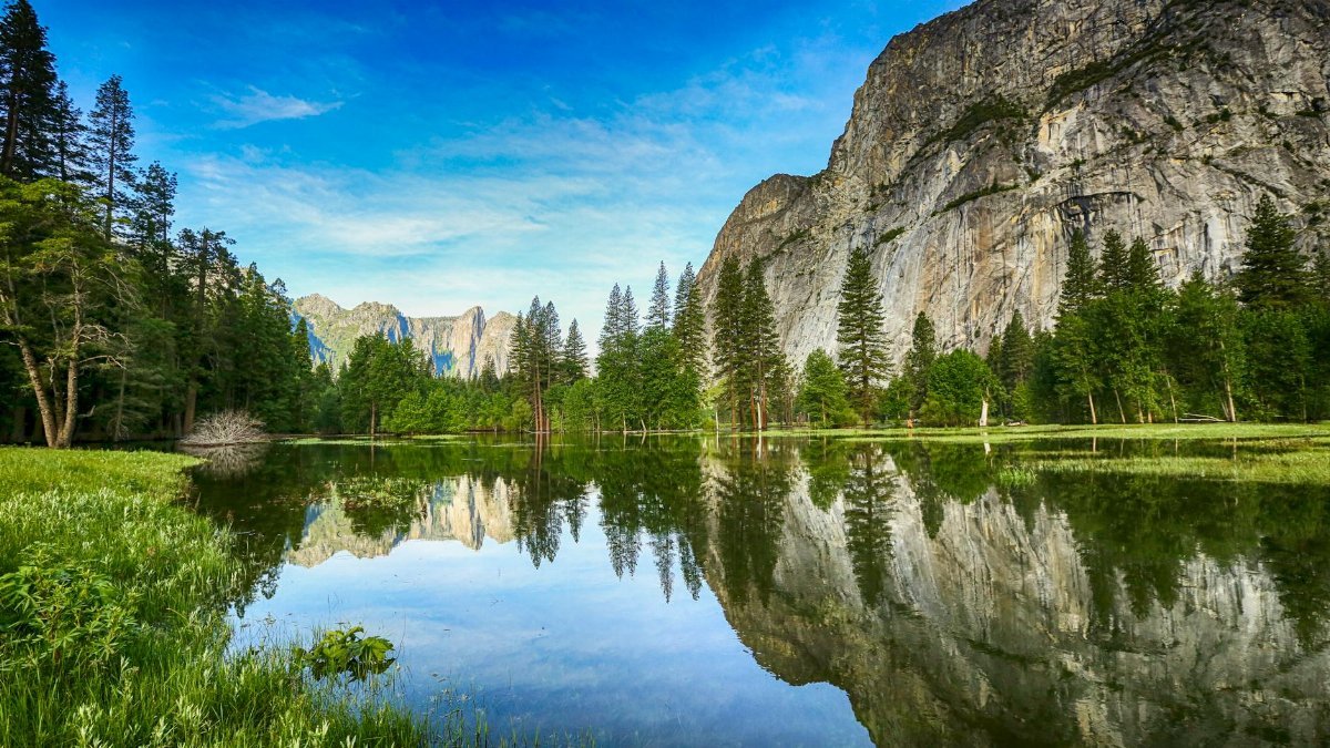 Stunning reflection of mountains and trees in Yosemite Valley's Mirror Lake during daytime.