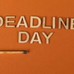 Conceptual image of a deadline with wooden letters and burnt matchstick on orange background.