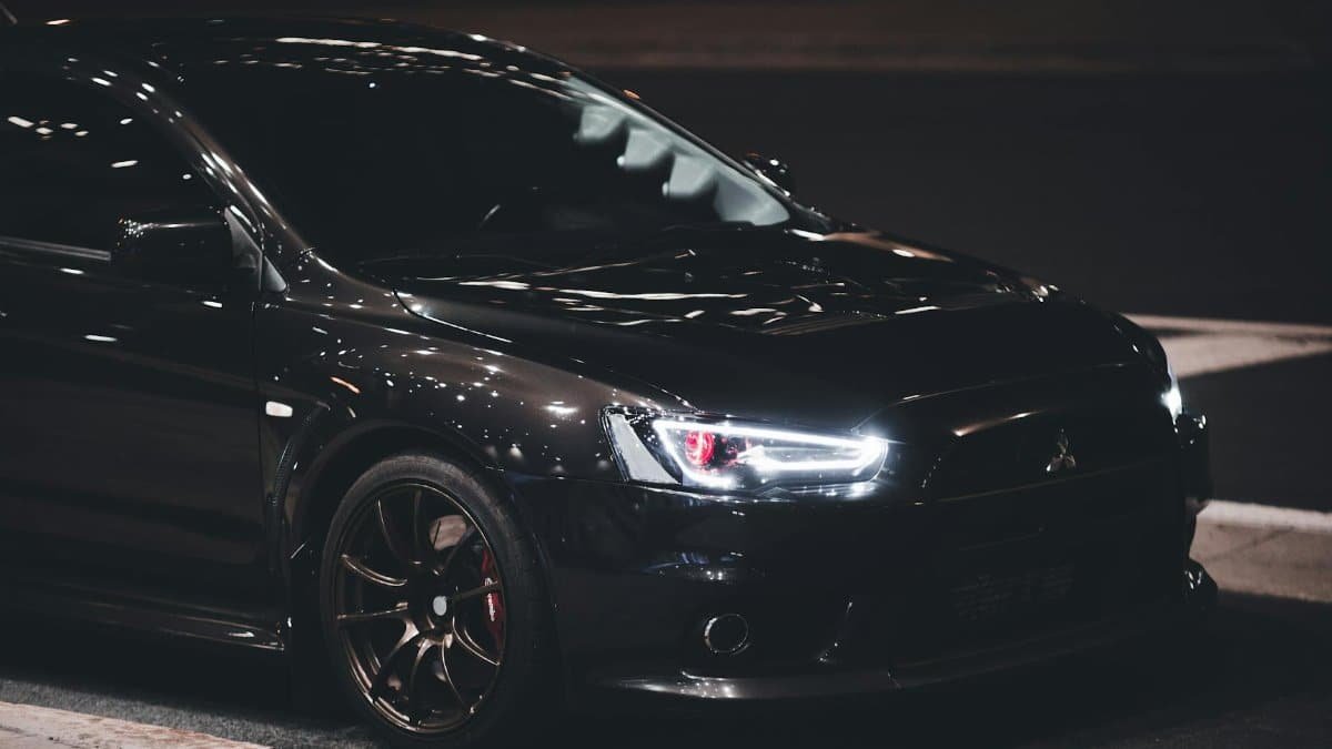 A black Mitsubishi Lancer Evolution X sports car parked at night, showcasing its modern design.