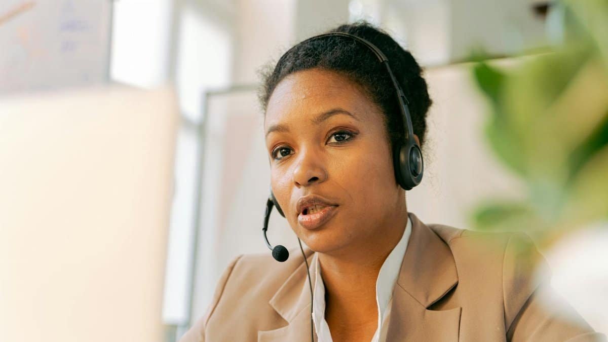 African American woman working in a call center with a headset on, providing customer support.