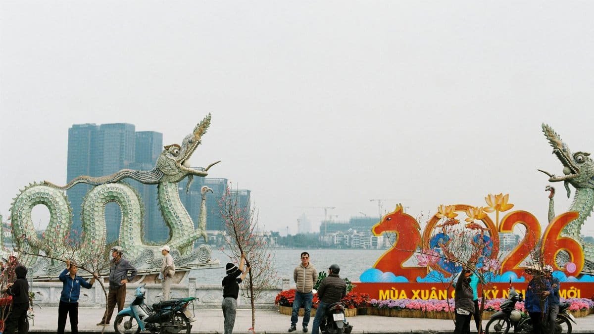 People preparing for Lunar New Year 2026 by a dragon statue along a lakeside.