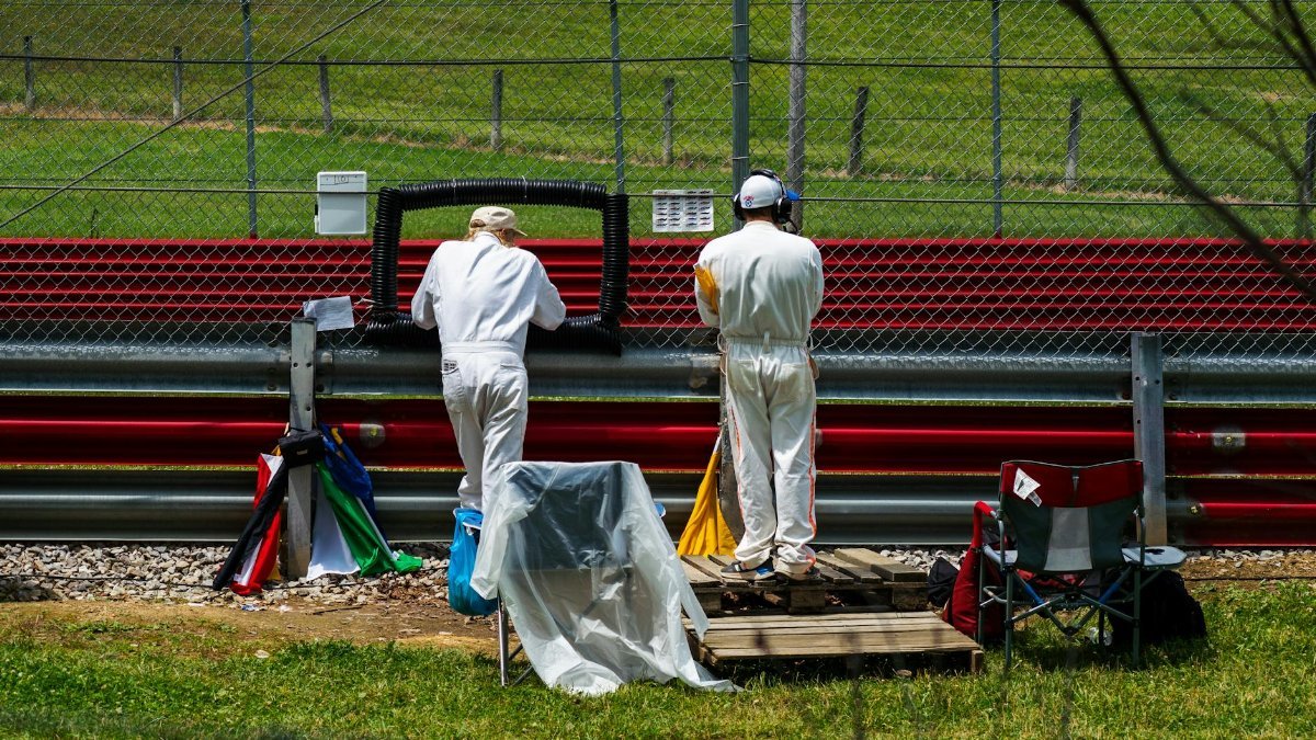 Race officials in coveralls at a Lexington, OH track, managing flags and equipment