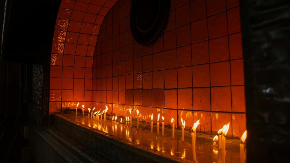 Serene image of candles burning in an indoor altar setting with a warm glow.