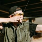 An archer concentrating as he draws his bow back, preparing to release his arrow during outdoor practice.