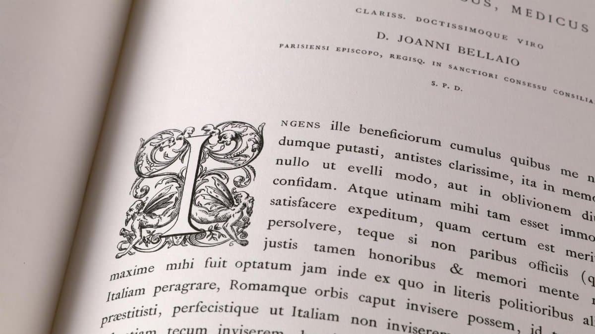Close-up of an open book with intricate Latin text and decorative initials.
