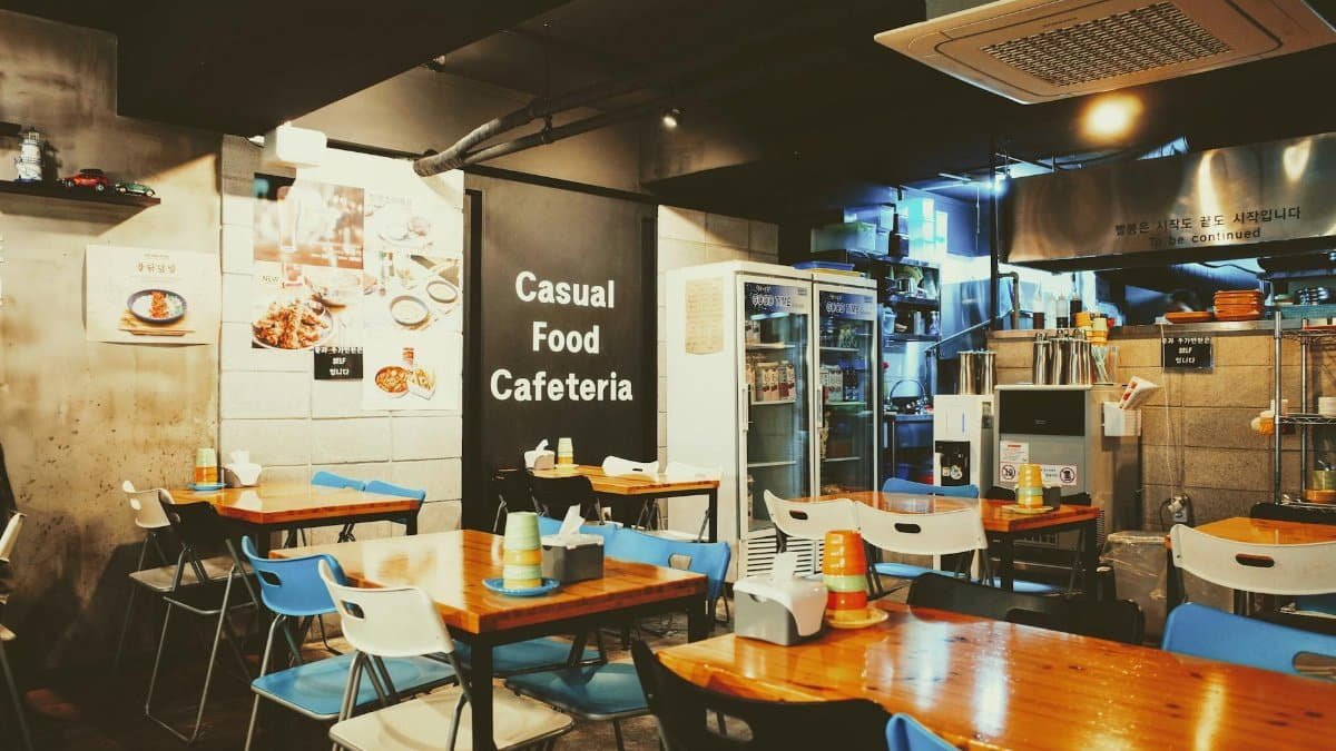 A cozy casual cafeteria interior with tables and chairs, located in Busan, South Korea.