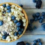 Top view of a nutritious breakfast bowl with blueberries, blackberries, and cereal on a rustic wooden table.