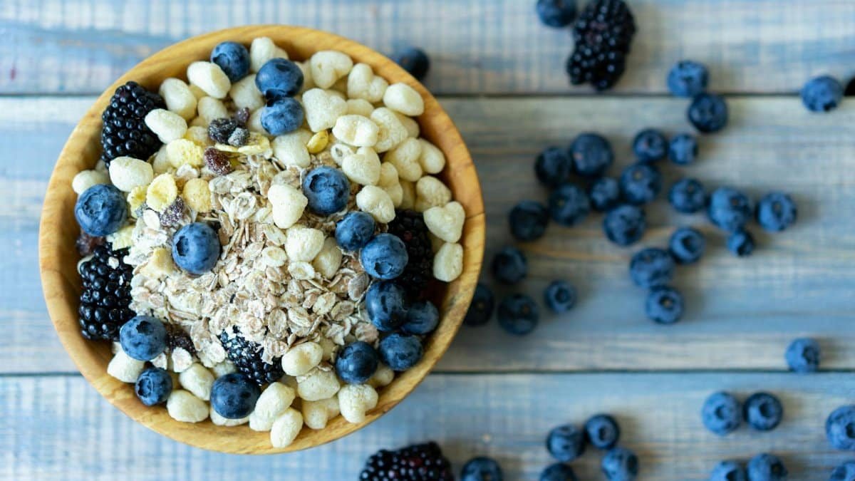 Top view of a nutritious breakfast bowl with blueberries, blackberries, and cereal on a rustic wooden table.