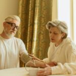 An elderly couple at home measuring blood pressure with a digital monitor, depicting care and health awareness.