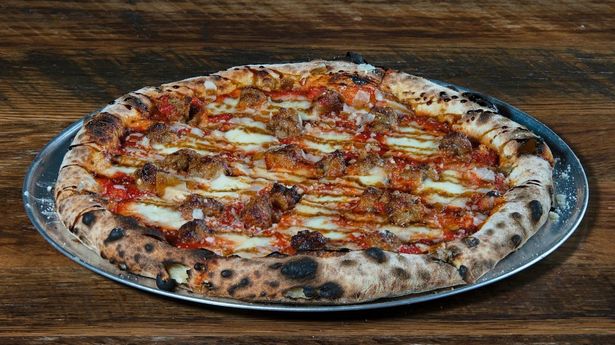 Delicious wood-fired pizza with Italian sausage on a metal tray. Perfect for food lovers.