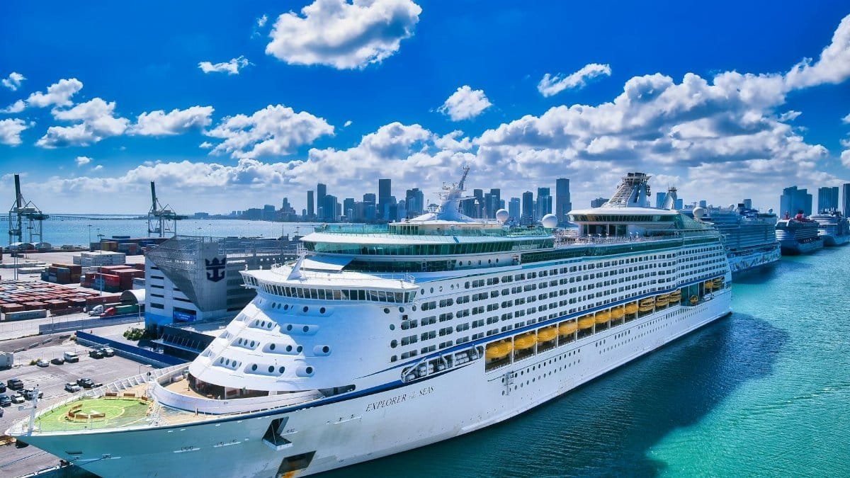 A luxurious cruise ship moored at the bustling Miami port with the city skyline in the background.