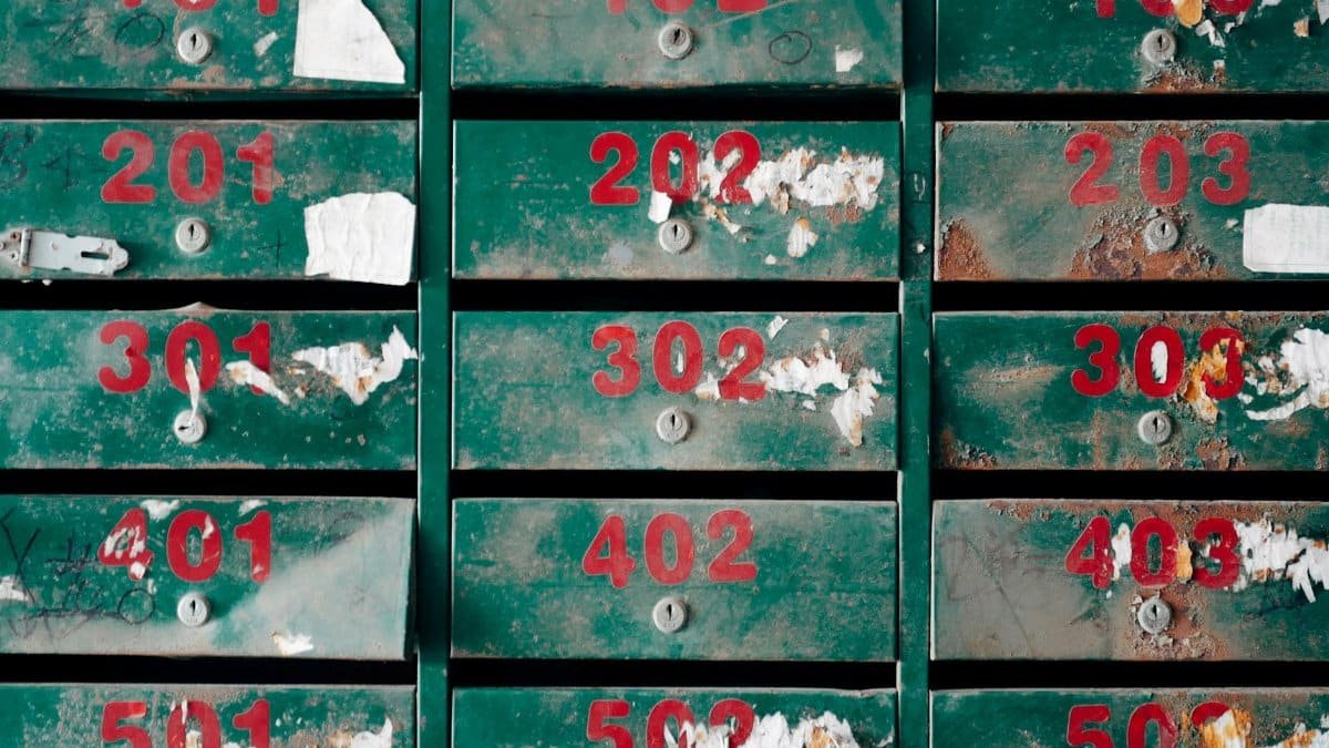 Old, rusty mailboxes with peeling paint and numbers, conveying neglect.