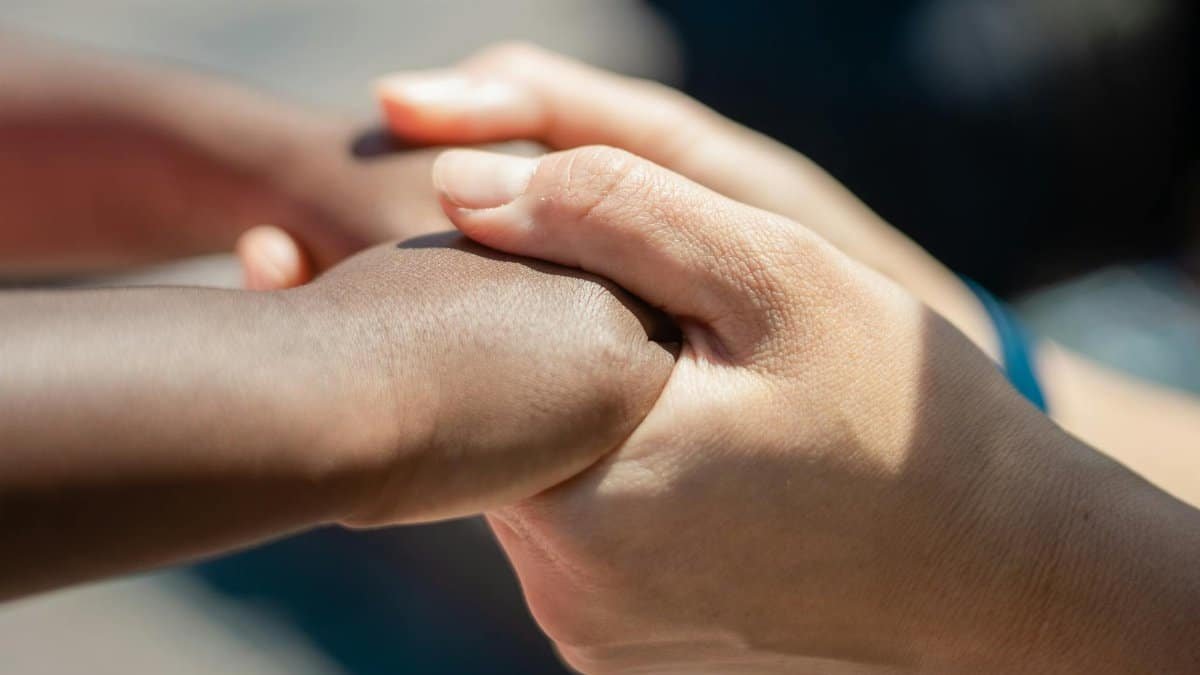 Close-up of diverse hands holding, symbolizing unity and compassion.