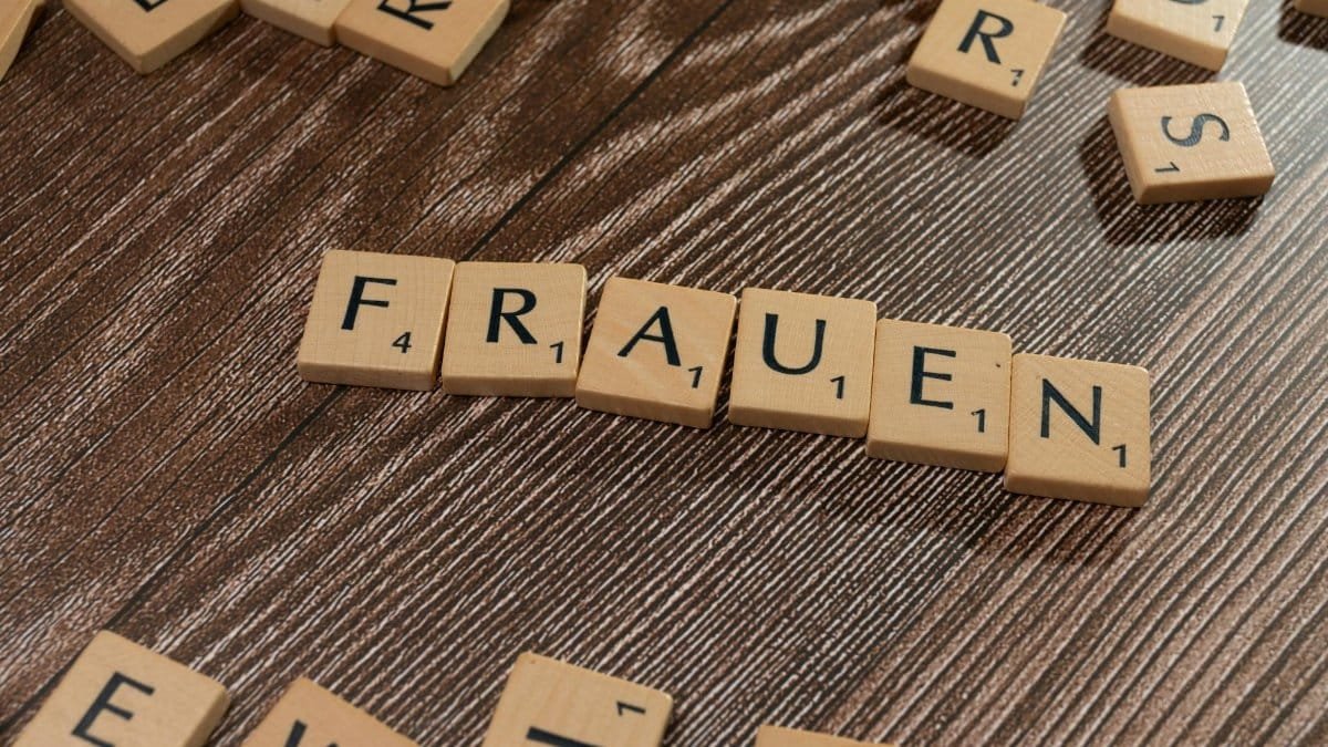 Close-up of wooden tiles spelling 'Frauen' on a wooden surface, high angle.