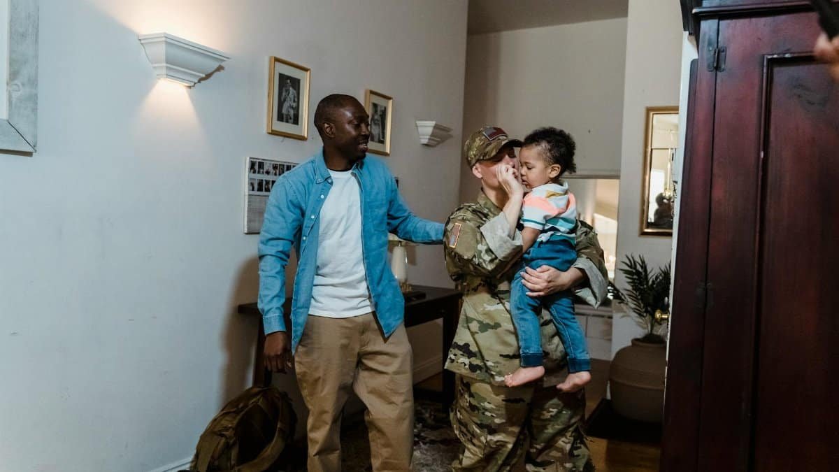 Emotional family reunion with a military mother, father, and child celebrating homecoming indoors.