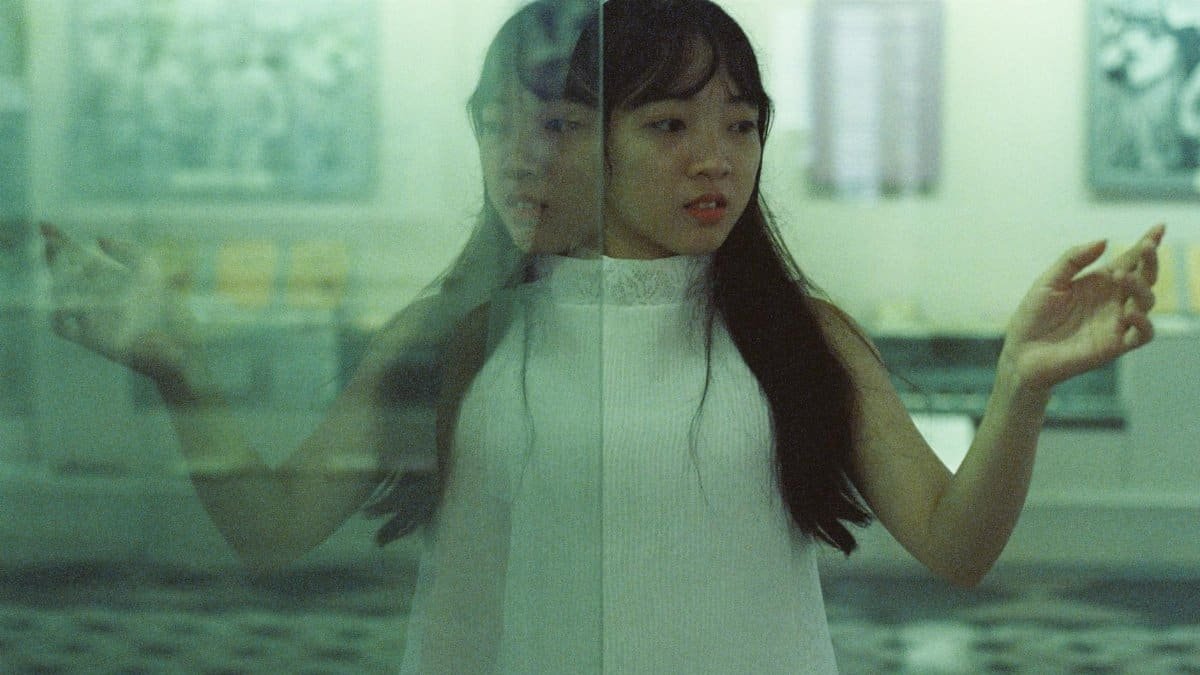 A woman gazes at her reflection in a glass surface, creating an artistic and introspective moment.