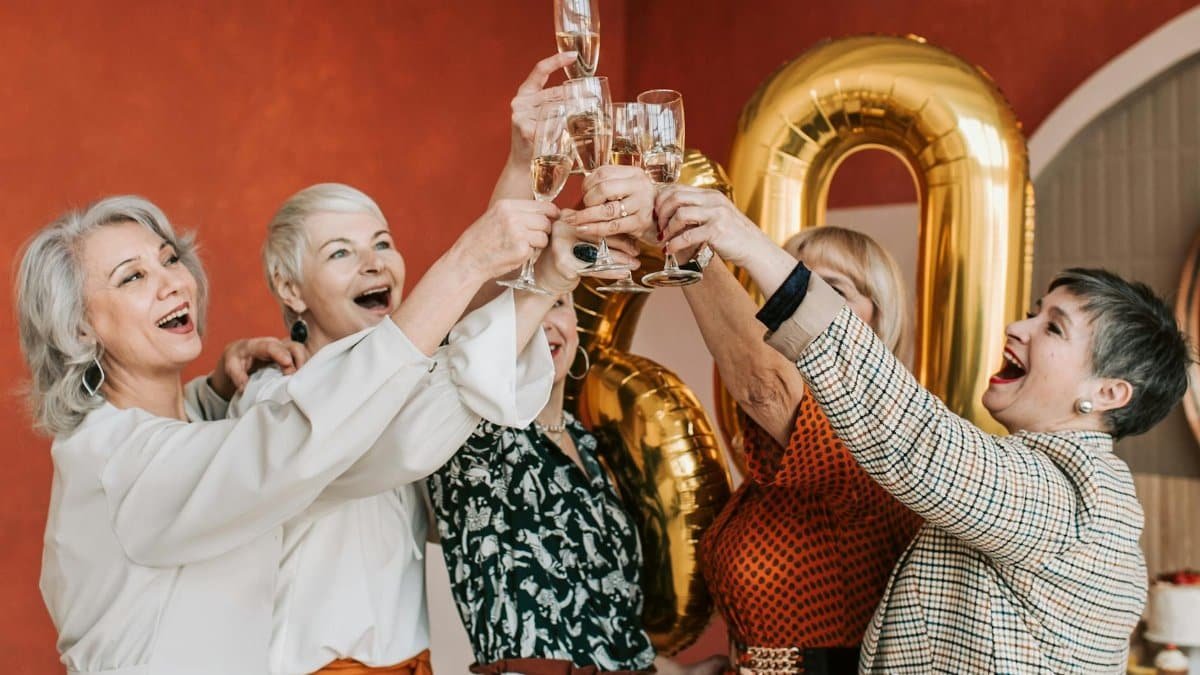 Group of senior women celebrating together with champagne in a festive indoor setting.