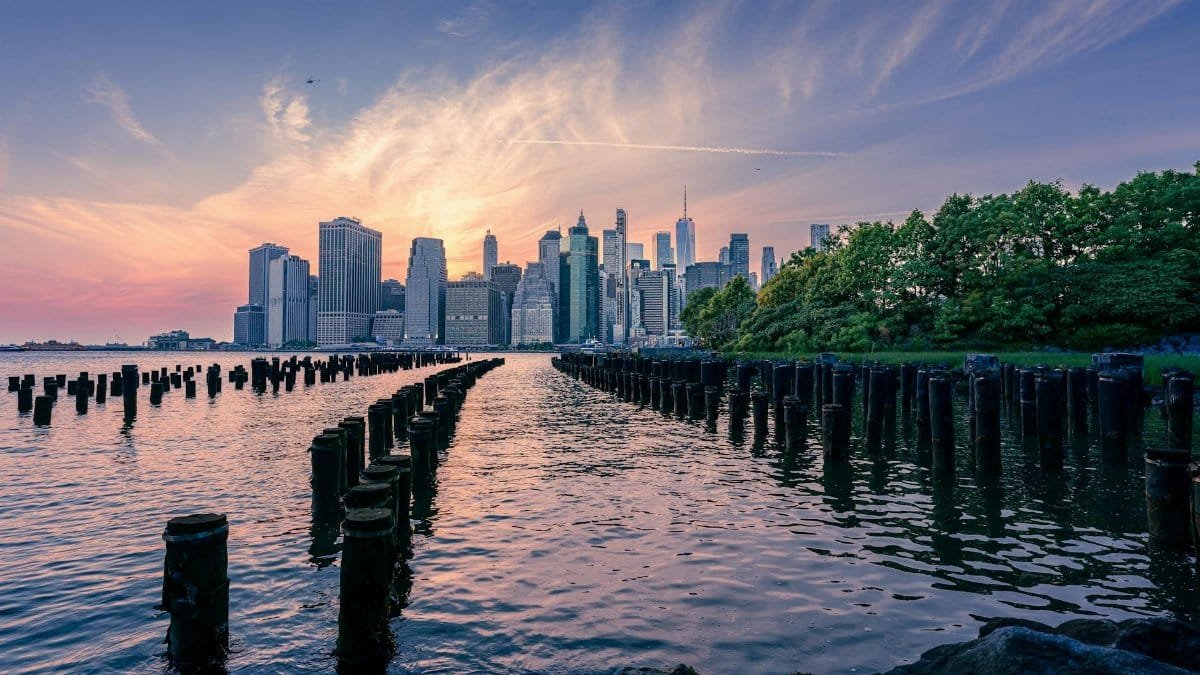 Scenic view of Manhattan skyline over water at sunset, captured from Brooklyn Bridge Park.