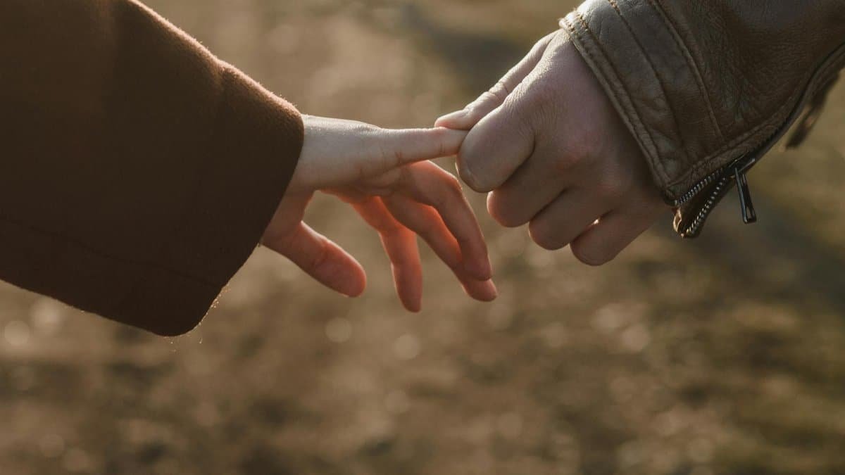 Close-up of two hands connecting, symbolizing love and connection in a warm setting.