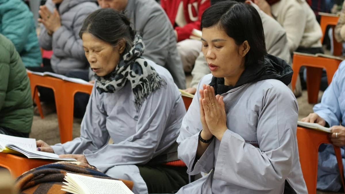 People gathered in meditation, wearing spiritual robes, focusing deeply in tranquil setting.