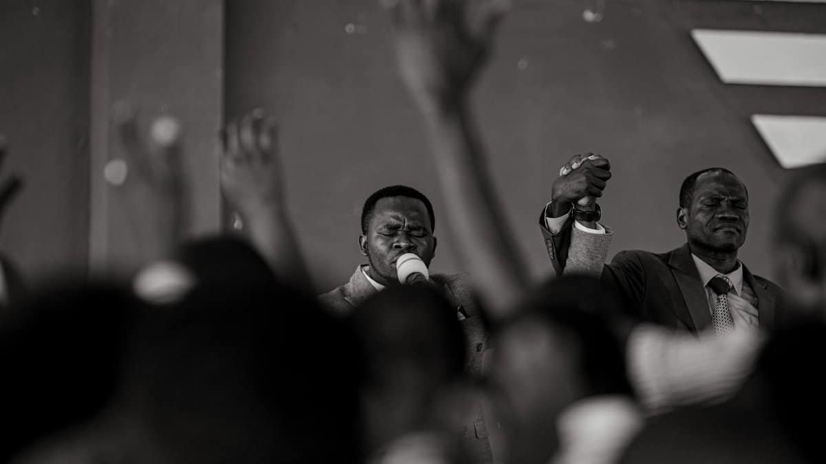 A spiritual gathering with men leading a church service in monochrome.