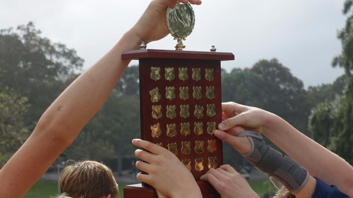 Group of young athletes raising a wooden trophy, symbolizing victory and teamwork.