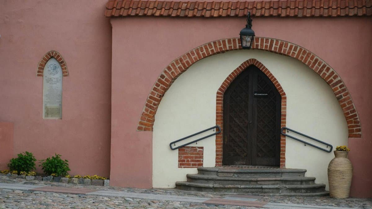 Charming entrance with brick arch and steps leading to a wooden door on a historic building.